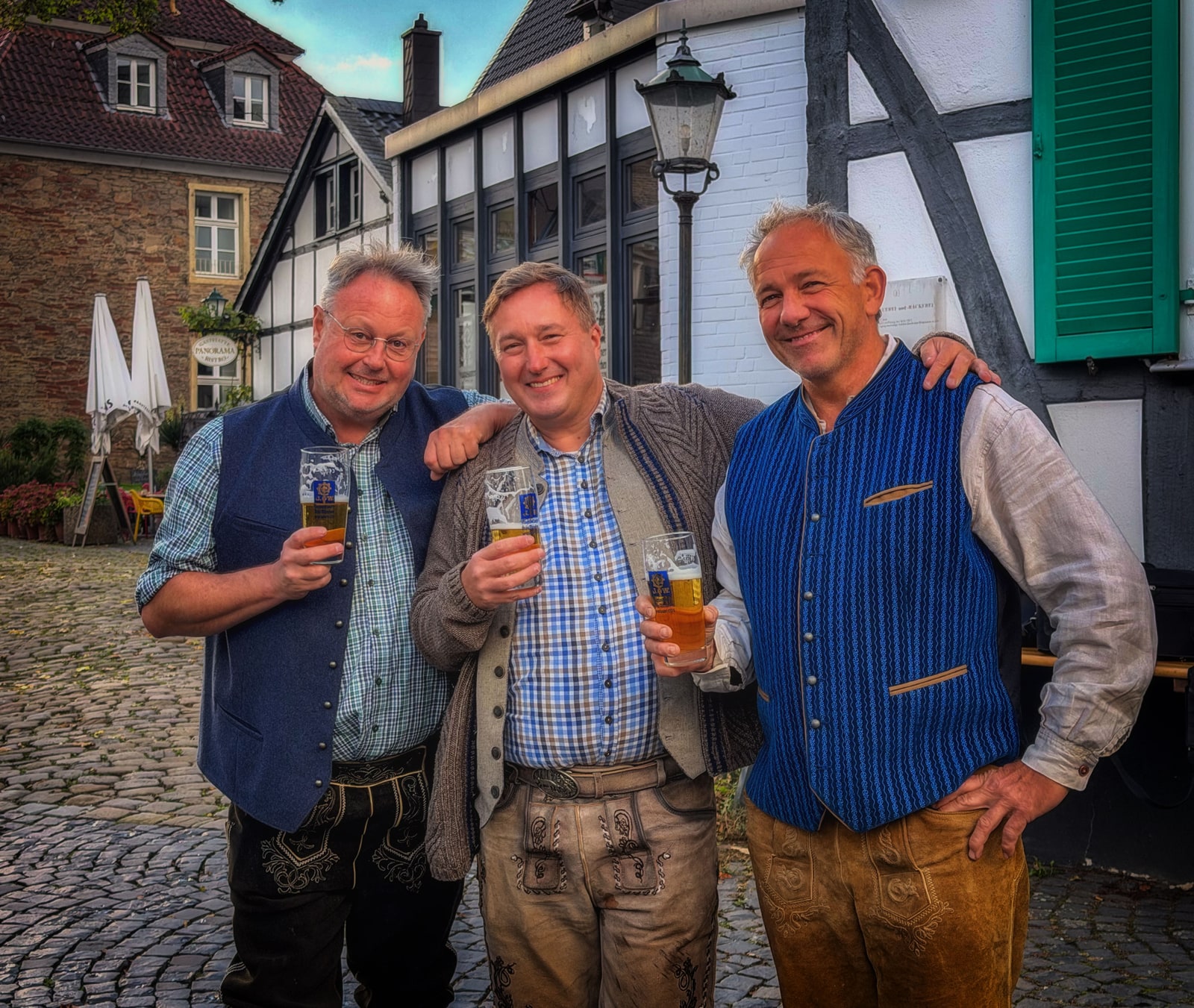 Peter Dembler, Thorsten Jahnke und Axel Demtröder stehen mit Biergläsern vor dem Wirtshaus Pfingsten.